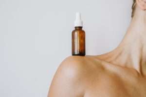 Woman with the serum bottle on her shoulder